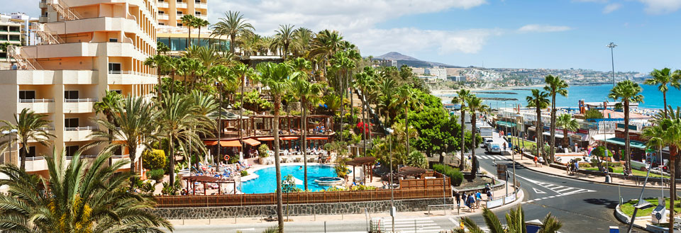 Bild av ett semesteranläggning på Maspalomas med palmer, en pool och människor som njuter av solen. Havet i bakgrunden.