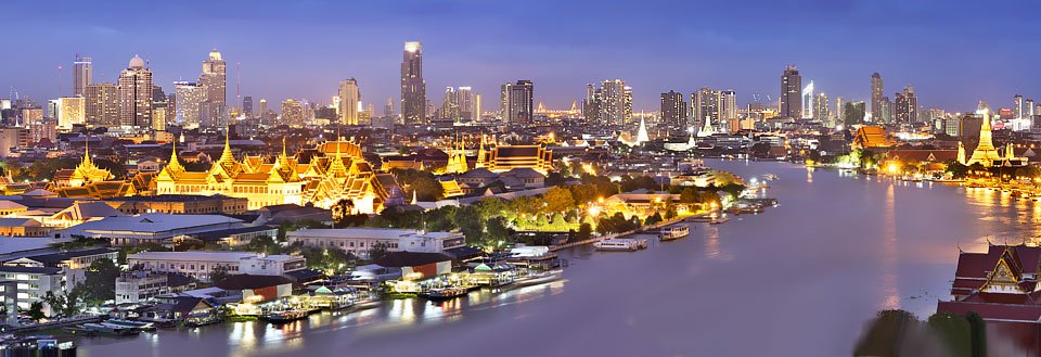 Panoramavy över en Bangkok vid kvällstid med upplysta byggnader och Chao Praya-floden som skär genom staden.