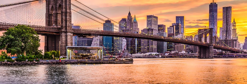 Bild av en bro med  New Yorks skyline bakgrunden vid solnedgång, spegling i vattnet.