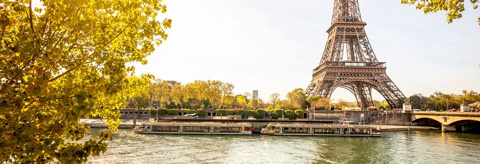 Eiffeltornet i Paris, Frankrike, med en sightseeingbåt på floden Seine och gyllene höstlöv.