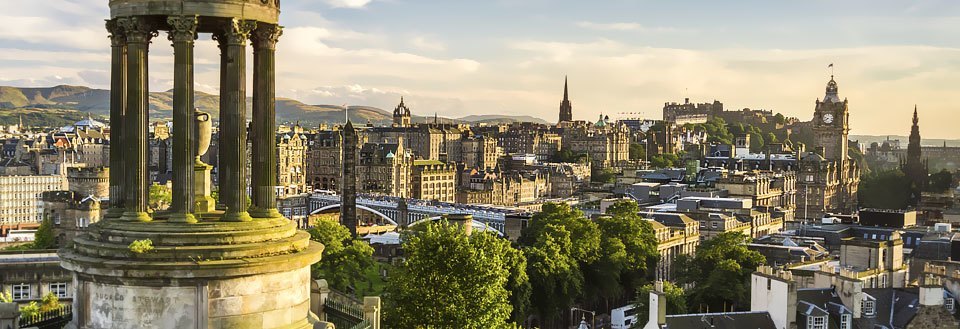 Panoramavy över Edinburgh med varierad arkitektur och gröna kullar i bakgrunden.