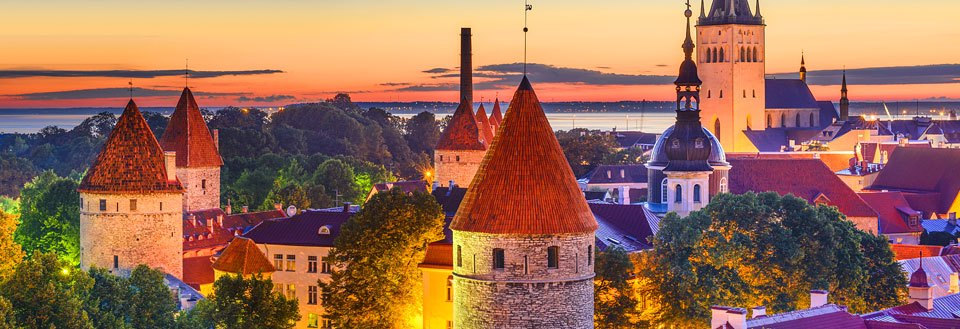 Kvällsbild af Tallinn med torn och spiror mot en solnedgångsbakgrund.