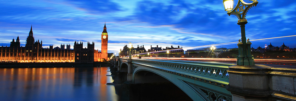 Westminster Bridge och Big Ben under skymningstid med ljusstrimmor och upplyst parlament.