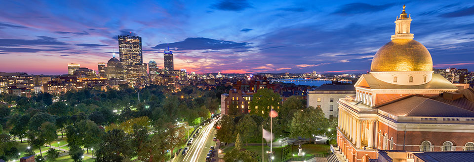 Skymning över stadens skyline med upplysta byggnader och en praktfull kupol i förgrunden.