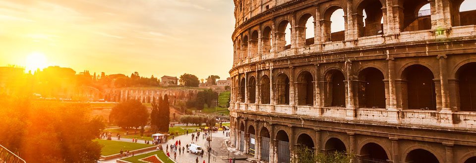 Colosseum i Rom i solnedgången med promenerande människor i närheten.