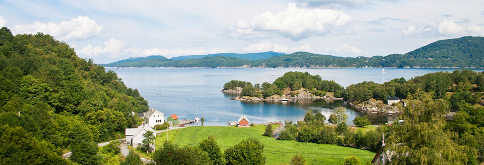 Idyllisk norsk fjord med hus, gröna områden och små öar.