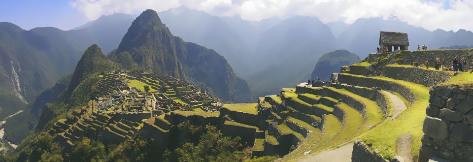 Machu Picchu med terrasserade fält och dimmiga berg i bakgrunden.