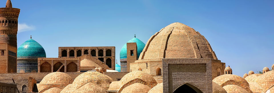 Antika kupoler och minareter mot en klarblå himmel, vilket antyder en historisk islamisk byggnad.